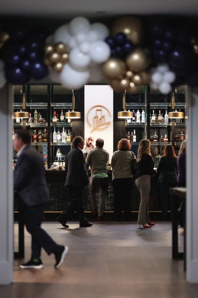 Guests gathered at The City Club of Greenville with balloon arch and gold-lit bar in the background